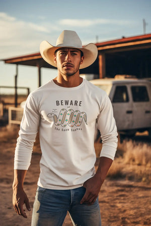  Cowboy wearing a long sleeve Snowsnake t-shirt and cowboy hat, standing by a truck and lean-to