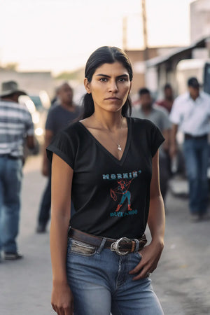 Woman wearing a v-neck Mornin' Buckaroo t-shirt with a crowd of cowboys and western folk blurred in the background