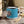Enamel camp mug with blue body, black rim, colorful rooster feather artwork