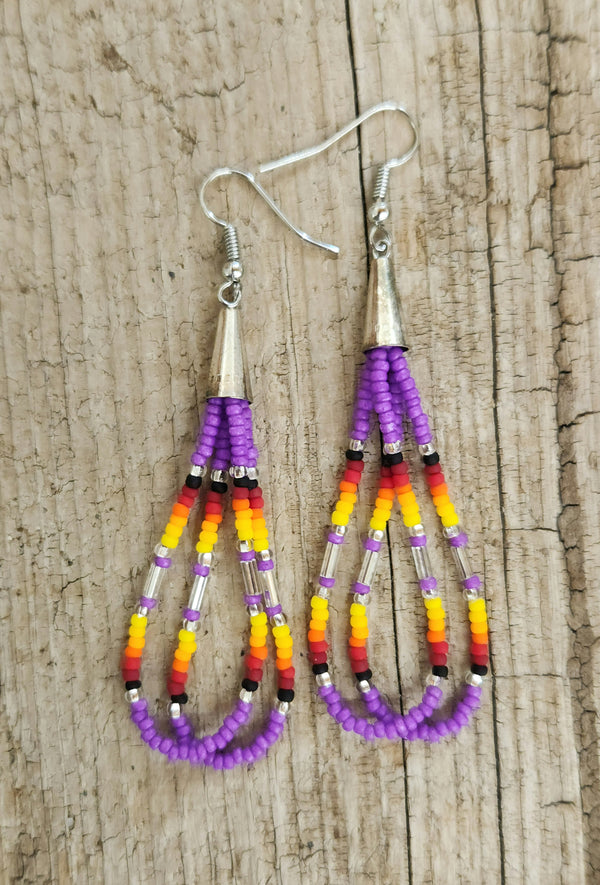 Shoshone-crafted purple cone dangle earrings with red, orange, and yellow bead accents on rustic wood background