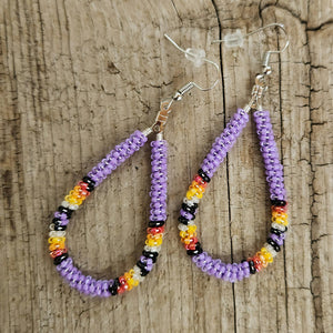Native-made beaded purple oval hoop earrings by Kalli Tillman with yellow, orange, red, black, and white accents