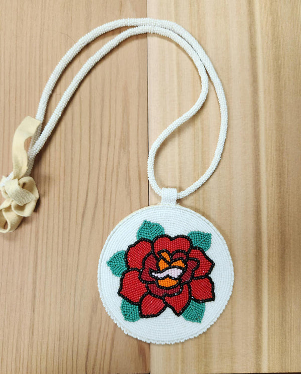 Beaded necklace with white cord and round medallion, red rose with green leaves