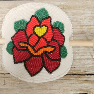 Hand-beaded Shoshone Rose barrette by Eastern Shoshone artist Anita Setzer, featuring vibrant red, green, and yellow beads on wood background.