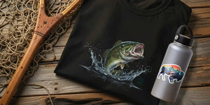 Rustic flat lay of a black Western wear t-shirt with a bass fish graphic beside a gray stainless steel water bottle featuring a buffalo landscape sticker.