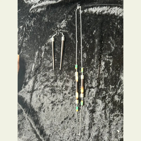 
Handcrafted African porcupine quill necklace and matching earrings set by Amie Loiselle, featuring sterling silver chain and colorful trade beads on a black velvet background.