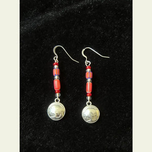 Double R Western exclusive earrings by Amie Loiselle featuring red and blue trade beads with silver-plated buffalo nickel charms, displayed on a black velvet background.