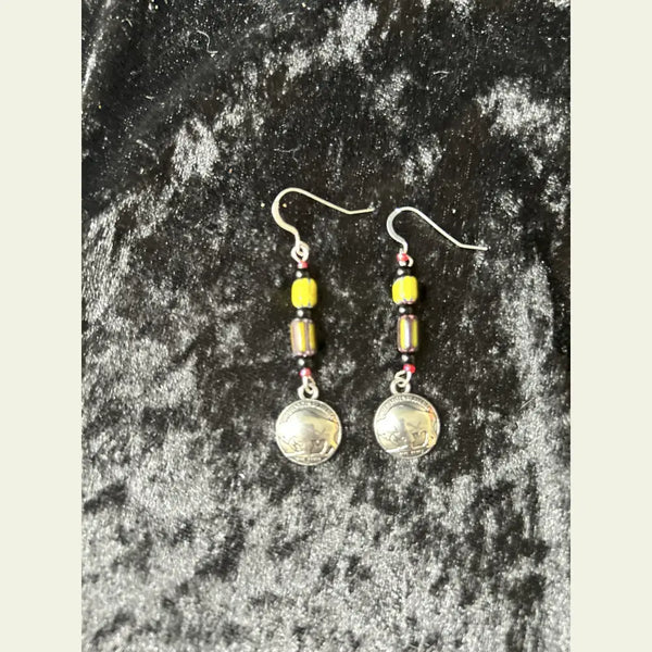 Double R Western exclusive earrings by Amie Loiselle featuring yellow and black trade beads with silver-plated buffalo nickel medallions, displayed on a black velvet background.