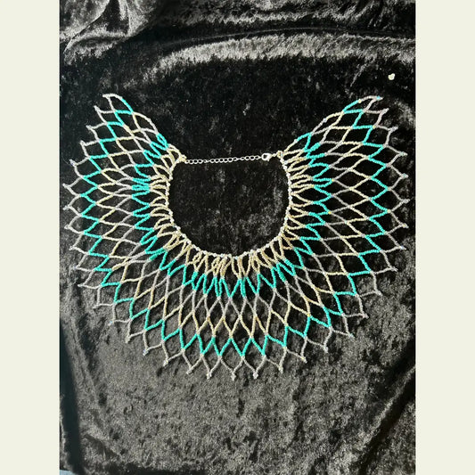 Handwoven seed bead and cut crystal collar necklace by artisan Amie Loiselle, featuring turquoise, silver, and iridescent beads on a black velvet background.