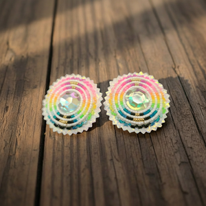 Hand-beaded white neon stud earrings with iridescent crystal centers on a wooden surface.