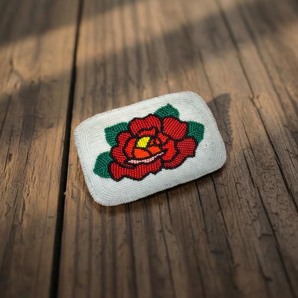 Beaded belt buckle with white base and red rose design in green leaves