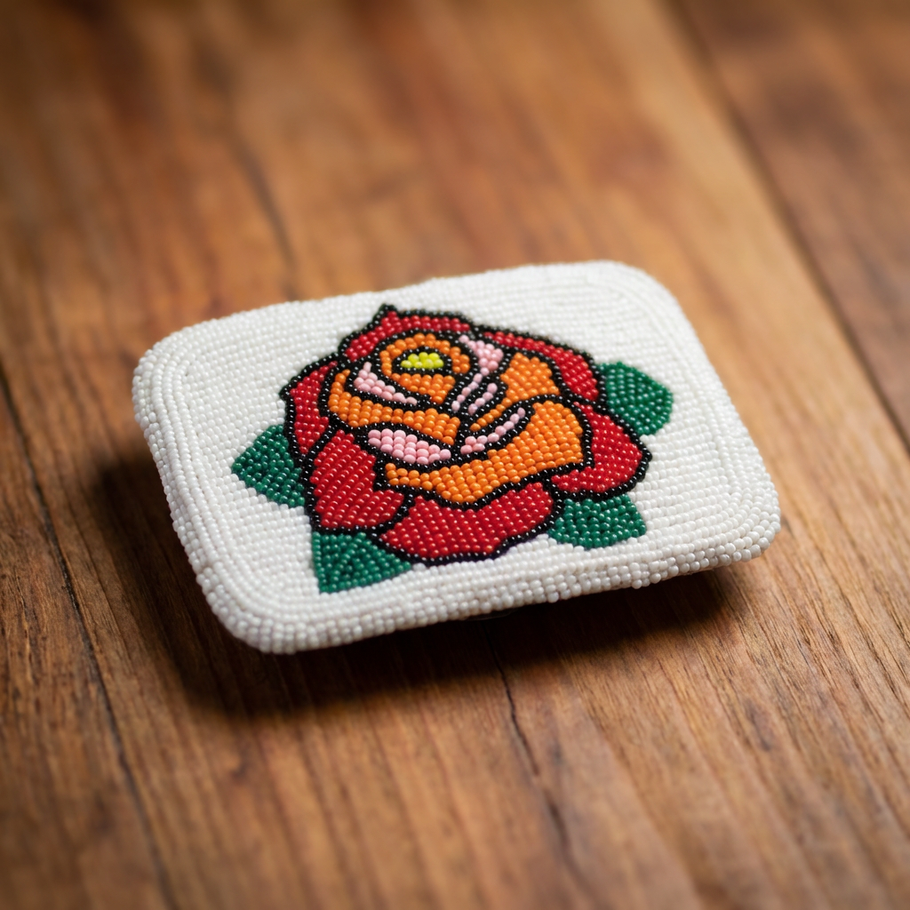 Hand-beaded Shoshone Rose belt buckle by Eastern Shoshone artist Anita Setzer, featuring a vibrant red, orange, and yellow rose with green leaves on a white beaded background, photographed on a rustic wood background.