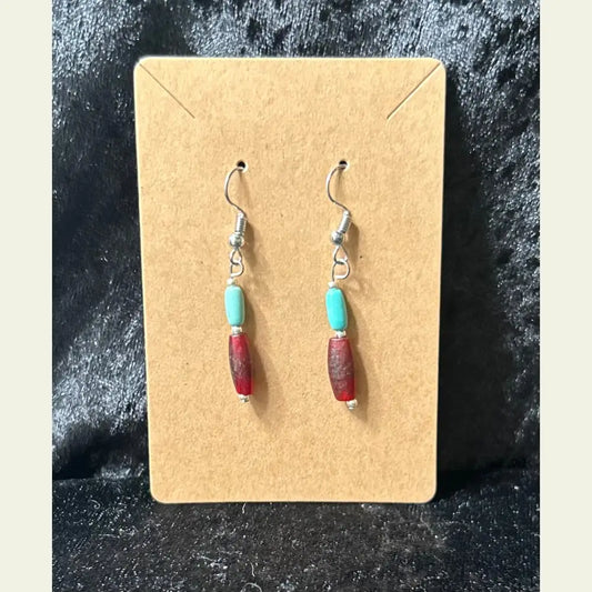 Handcrafted turquoise and red accent bead dangle earrings by artisan Amie Loiselle, displayed on a black velvet background.