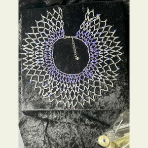 Handwoven small collar necklace by Amie Loiselle, featuring a netted design with glass and seed beads in purple and silver tones, displayed on a black velvet background.
